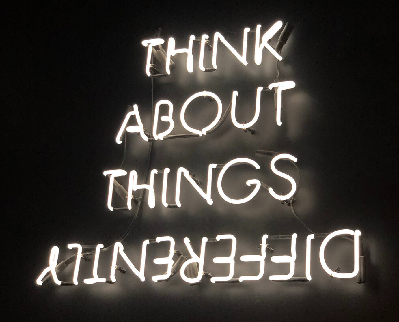 Neon sign photo spelling 'Think About Things Differently' by Ivan Bertolazzi.